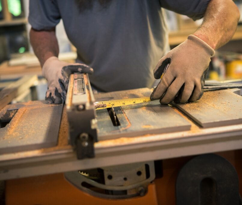 Wood artist in workshop, using woodworking machinery, mid section